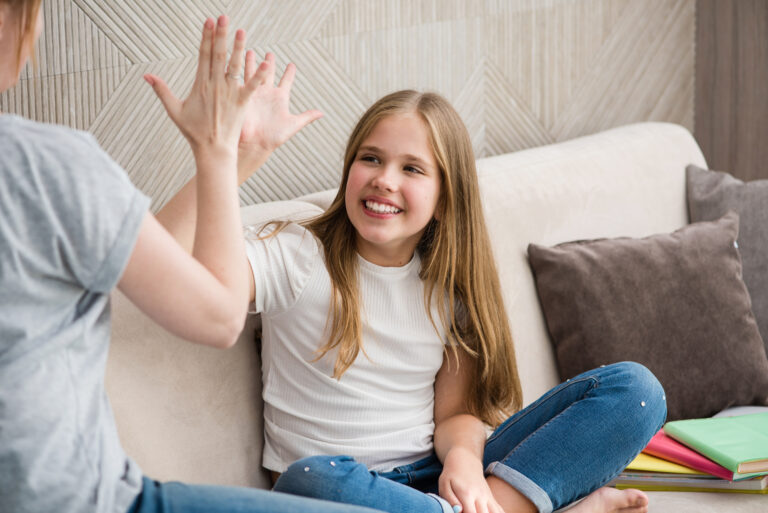 Cute young girl and her mother are giving each other high five - Benefits of playing games - FunFamilyGameNight.com