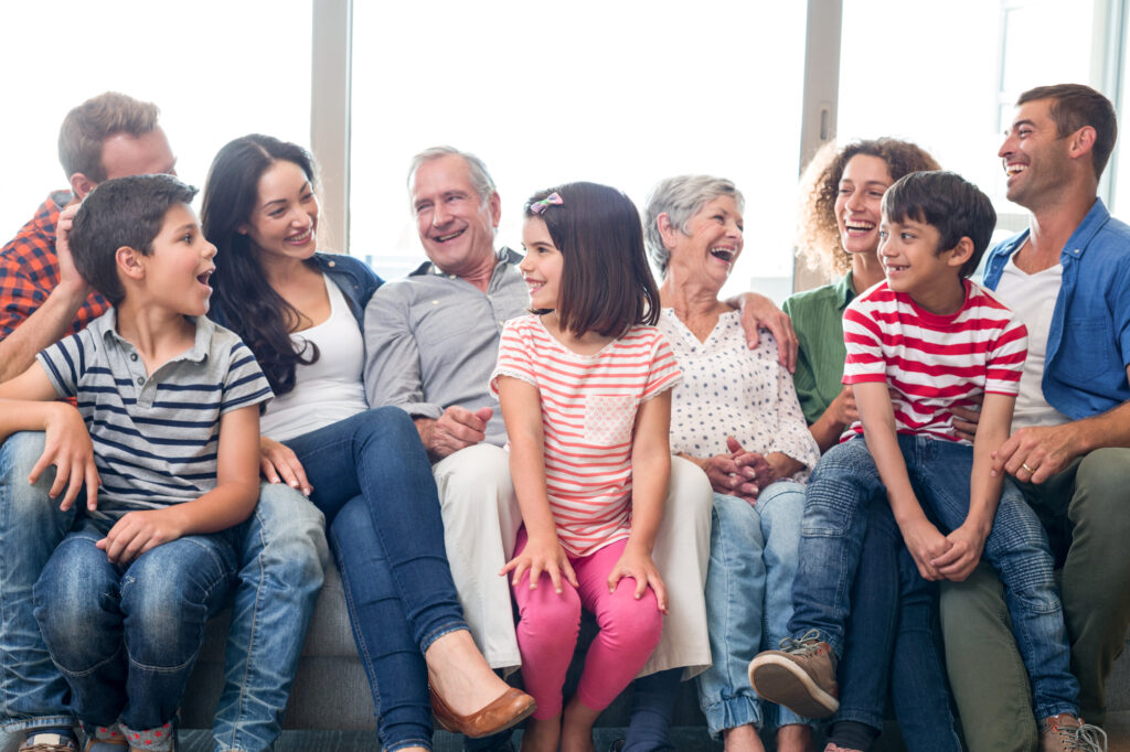 Multigenerational family sitting on couch talking and laughing