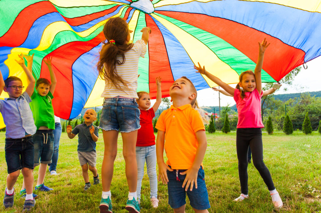 Kids playing outdoors with large parachute - FunFamilyGameNight.com